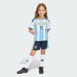 Equipación de niño de la primera camiseta de Argentina 26 de Messi. Kit infantil albiceleste con el dorsal 10 del campeón del mundo.