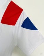 Camiseta blanca Adidas estilo retro con hombros rojos y azules y flor de lis dorada, supuestamente conmemorativa de París 2020. — foto 3