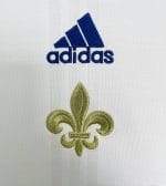 Camiseta blanca Adidas estilo retro con hombros rojos y azules y flor de lis dorada, supuestamente conmemorativa de París 2020. — foto 4