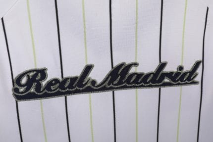 Camiseta estilo béisbol del Real Madrid, diseño blanco con rayas y detalles en negro y verde lima, con el escudo del club. — foto 2