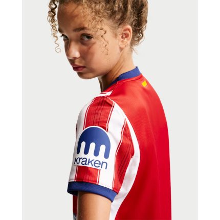 Conjunto infantil del Atlético de Madrid 2027, primera equipación. Camiseta y pantalón rojiblancos para los jóvenes fans.