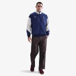 Vista frontal de la chaqueta cortavientos del Tottenham Hotspur 26/27 para adulto. Escudo del club y logos patrocinadores.