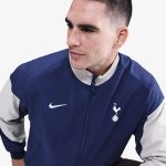 Vista frontal de la chaqueta cortavientos del Tottenham Hotspur 26/27 para adulto. Escudo del club y logos patrocinadores.