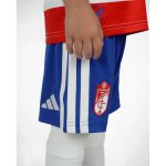 Primera equipación oficial del Granada CF para niños, temporada 2026-27. Conjunto de camiseta y pantalón rojiblancos.